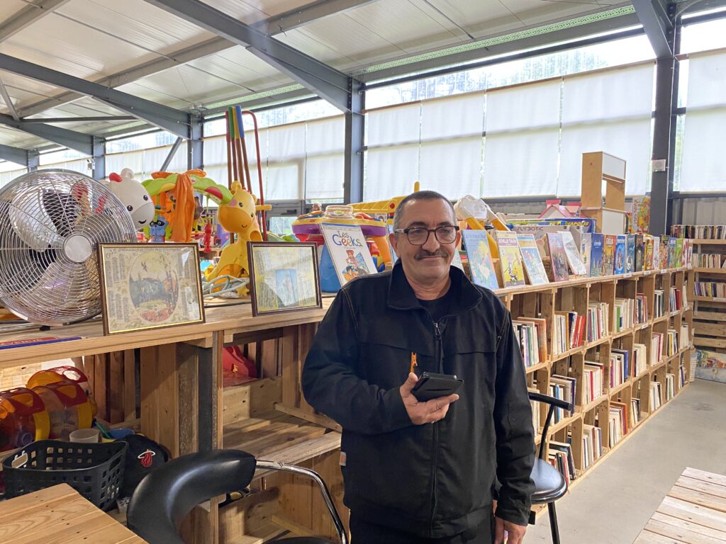 Sébastien devant son stand de livres à Emmaüs. 
