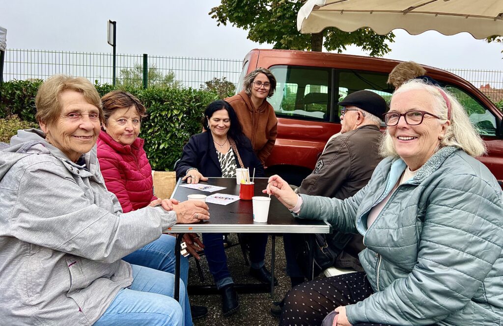 Séverine (au centre à l'arrière) et ciq habitués du marché attablés autour d'un café.